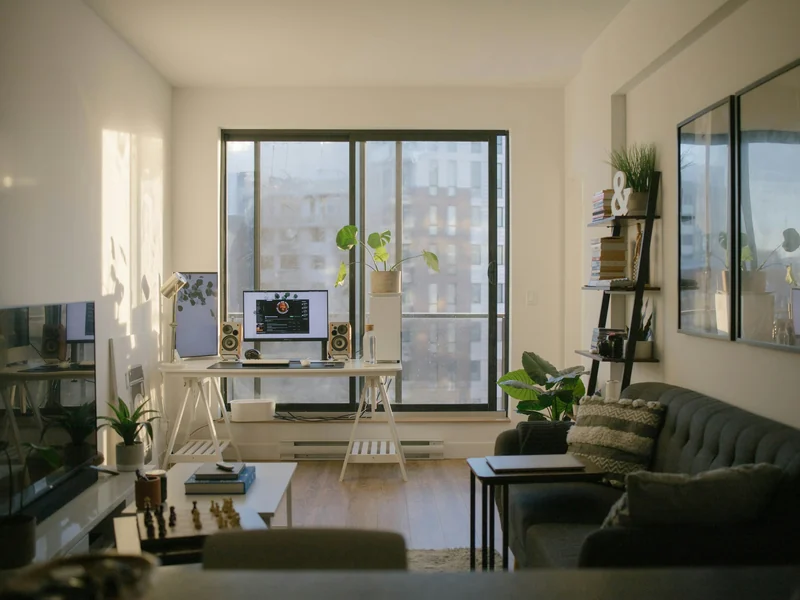 Sunlit apartment home office with a desk and computer beside large windows