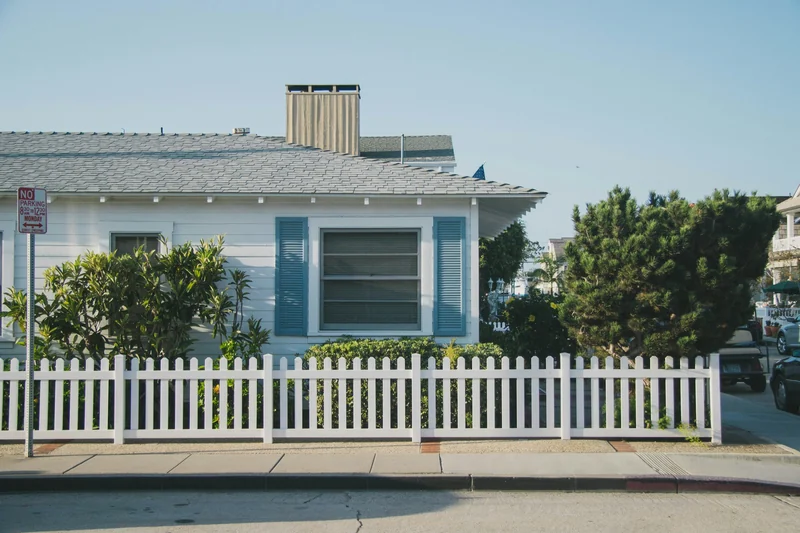 White beach cottage with blue shutters and a white picket fence