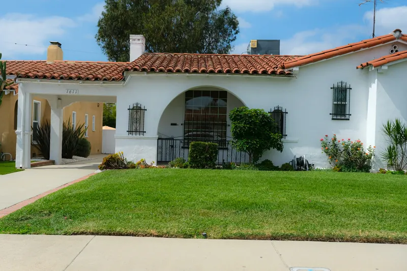 White stucco Spanish-style home with a red tile roof and arched entry