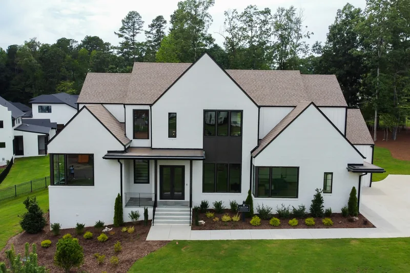 White modern farmhouse with black-framed windows and steep gables