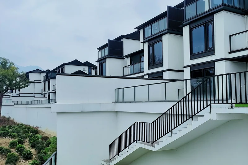 Modern white townhouses with black-framed windows and terraced balconies